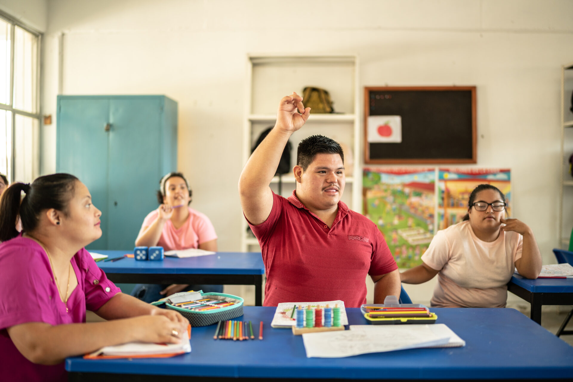 Young man raising his hand while asking question in the classroom at school.